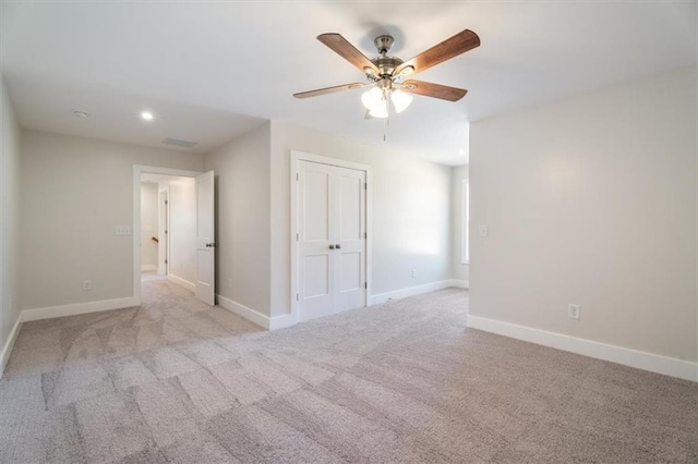 empty room featuring ceiling fan and light colored carpet