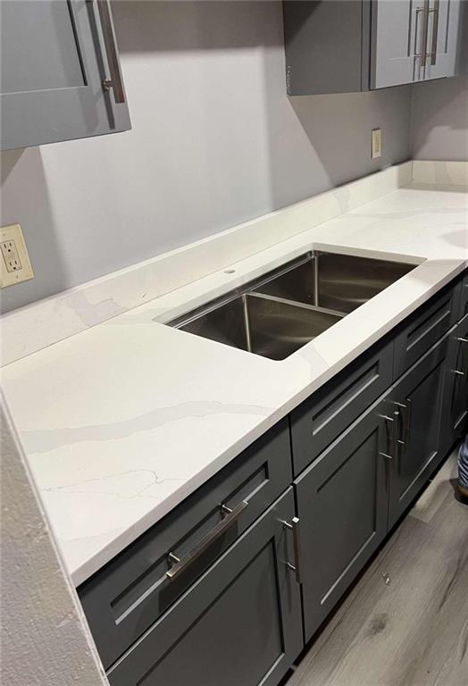 kitchen featuring light wood-type flooring, sink, and light stone counters