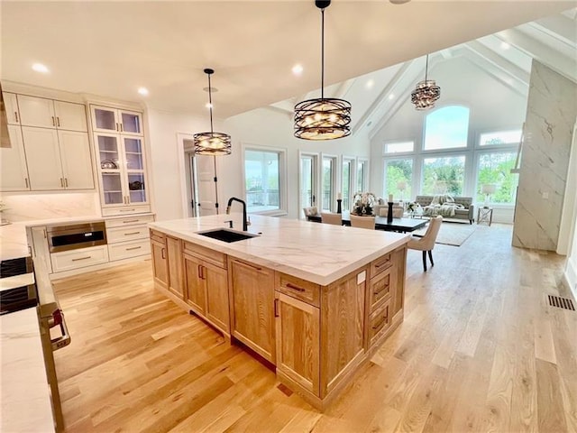 kitchen with a sink, plenty of natural light, light wood-style floors, high vaulted ceiling, and recessed lighting
