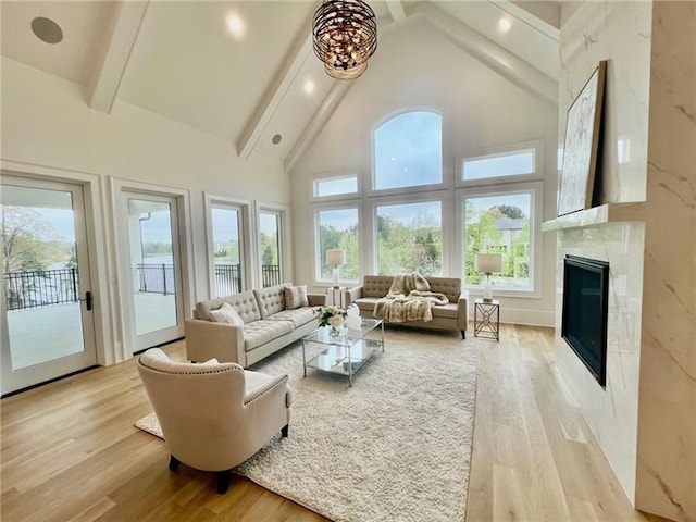 living area with healthy amount of natural light, high vaulted ceiling, beam ceiling, light wood-type flooring, and a high end fireplace