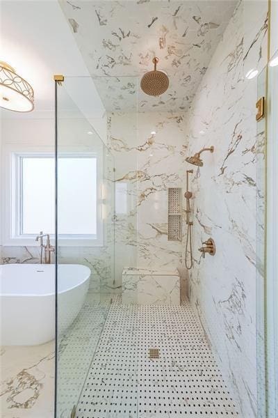 bathroom with a marble finish shower, a freestanding bath, and healthy amount of natural light