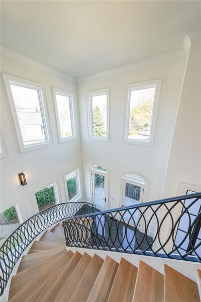 stairs with a high ceiling, healthy amount of natural light, and crown molding