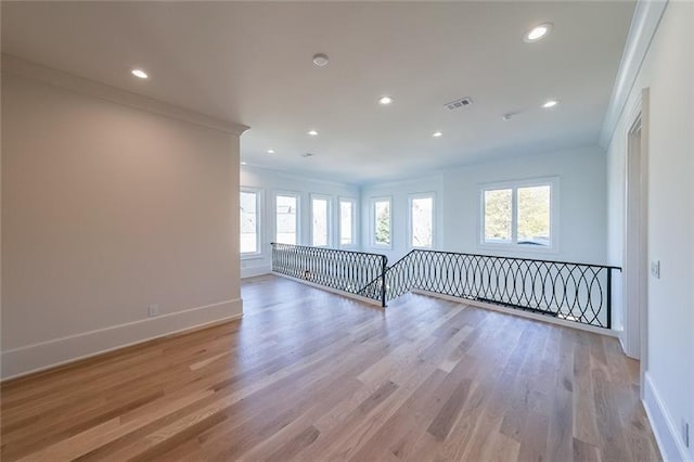 unfurnished living room featuring healthy amount of natural light, baseboards, light wood-style flooring, recessed lighting, and crown molding
