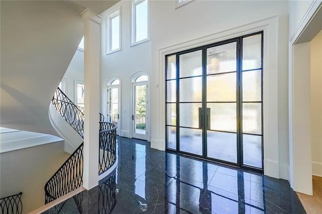 entryway featuring healthy amount of natural light, a high ceiling, baseboards, and stairway