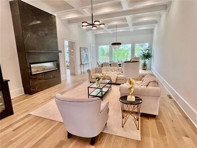 living room with light wood finished floors, coffered ceiling, baseboards, beam ceiling, and a large fireplace