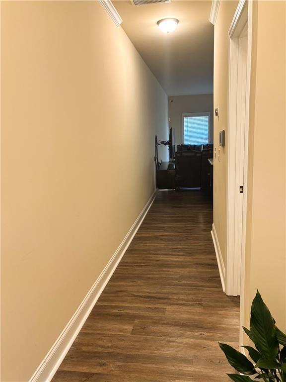hall with visible vents, baseboards, and dark wood finished floors