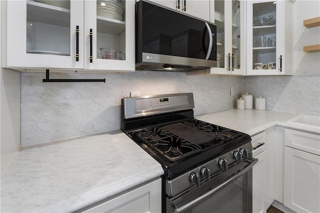 1491 Black Hickory Pl, Norcross, GA 30093 - kitchen with stainless steel gas range oven, white cabinetry, and glass insert cabinets