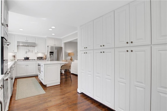 435 Grenock Cir, Atlanta, GA 30328 - kitchen with appliances with stainless steel finishes, white cabinets, a breakfast bar, recessed lighting, and a kitchen island