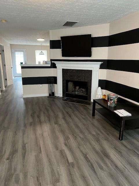 unfurnished living room featuring dark hardwood / wood-style floors, a fireplace, and a textured ceiling