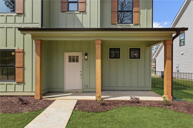 modern inspired farmhouse with covered porch, a lawn, board and batten siding, and a garage