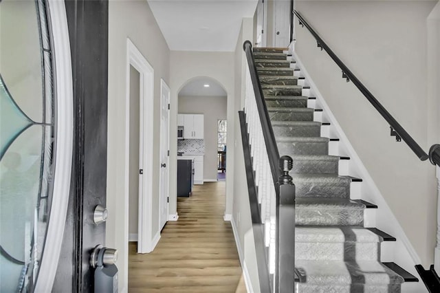 entryway with baseboards, arched walkways, and wood finished floors