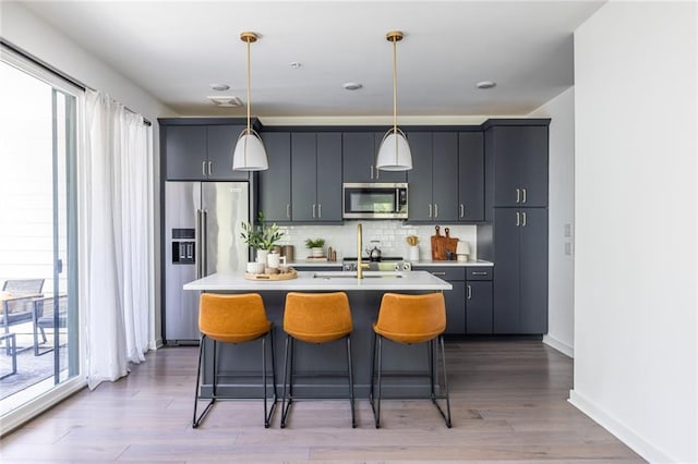 399 Pratt Dr SE, Atlanta, GA 30315 - kitchen with stainless steel appliances, light countertops, decorative backsplash, a center island with sink, and a breakfast bar area