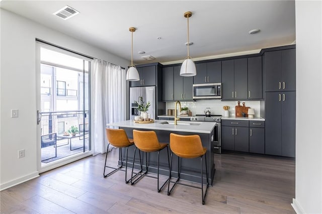 399 Pratt Dr SE, Atlanta, GA 30315 - kitchen with stainless steel appliances, a sink, light countertops, an island with sink, and a kitchen breakfast bar