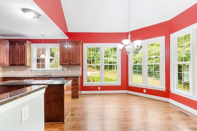 kitchen with a healthy amount of sunlight, tasteful backsplash, a sink, and decorative light fixtures