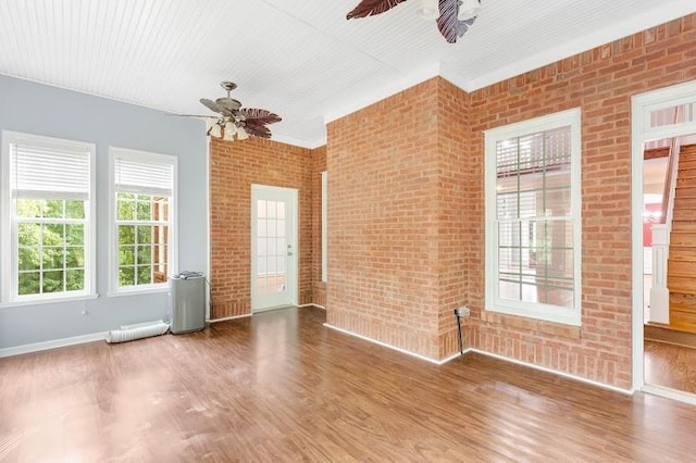 spare room featuring brick wall, ceiling fan, and wood finished floors