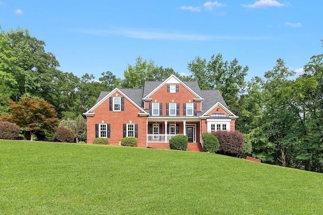 view of front facade with covered porch, brick siding, and a front lawn