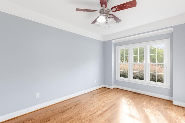 empty room featuring crown molding, wood finished floors, a ceiling fan, and baseboards