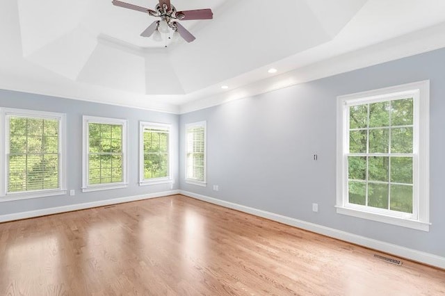 empty room with a healthy amount of sunlight, visible vents, baseboards, and wood finished floors