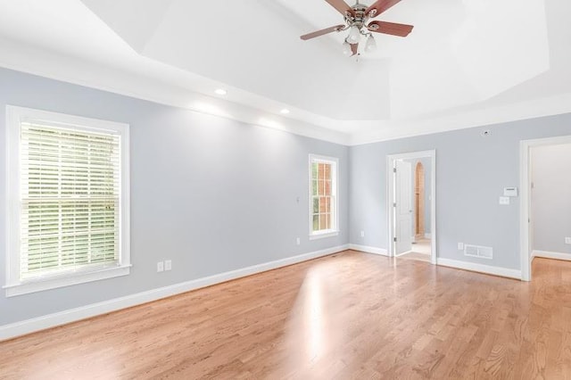 empty room featuring ceiling fan, wood finished floors, a raised ceiling, and baseboards