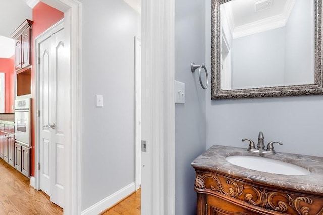 bathroom featuring visible vents, wood finished floors, vanity, and crown molding