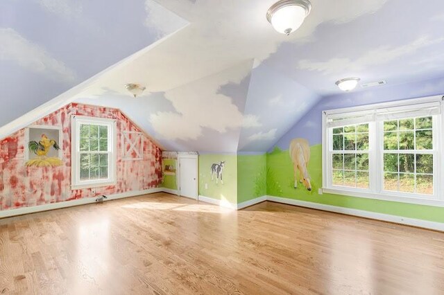 additional living space with light wood-type flooring and vaulted ceiling