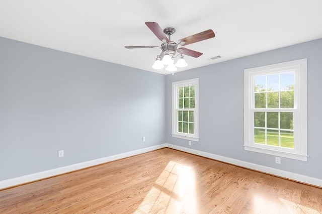 empty room featuring baseboards, visible vents, ceiling fan, and wood finished floors