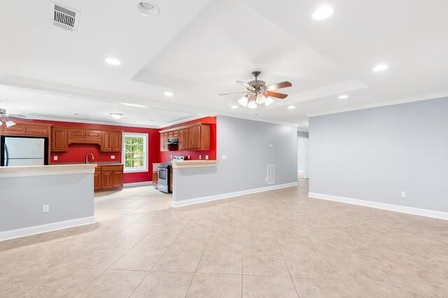 unfurnished living room with ceiling fan, a raised ceiling, ornamental molding, light tile patterned floors, and sink