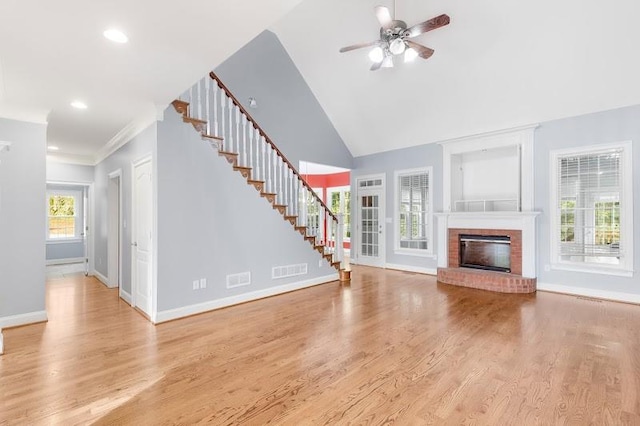 unfurnished living room featuring baseboards, visible vents, wood finished floors, stairs, and a brick fireplace