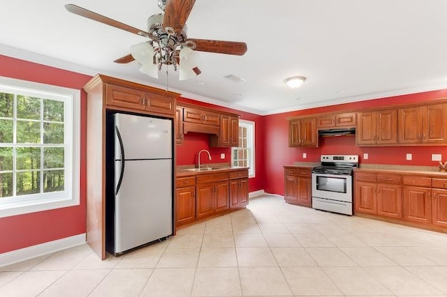 kitchen with ornamental molding, freestanding refrigerator, a sink, under cabinet range hood, and stainless steel electric range