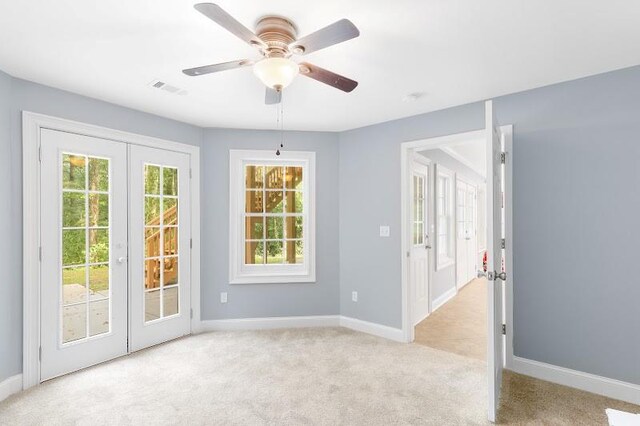 carpeted spare room with ceiling fan, a wealth of natural light, and french doors