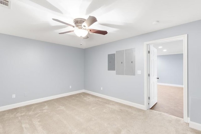 empty room with carpet, visible vents, ceiling fan, electric panel, and baseboards