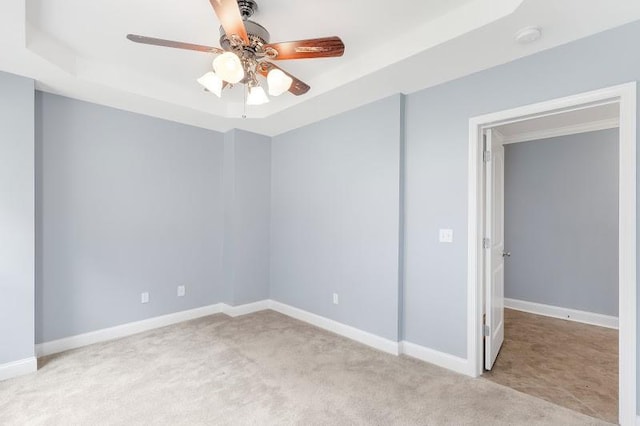 carpeted spare room with ceiling fan and a tray ceiling