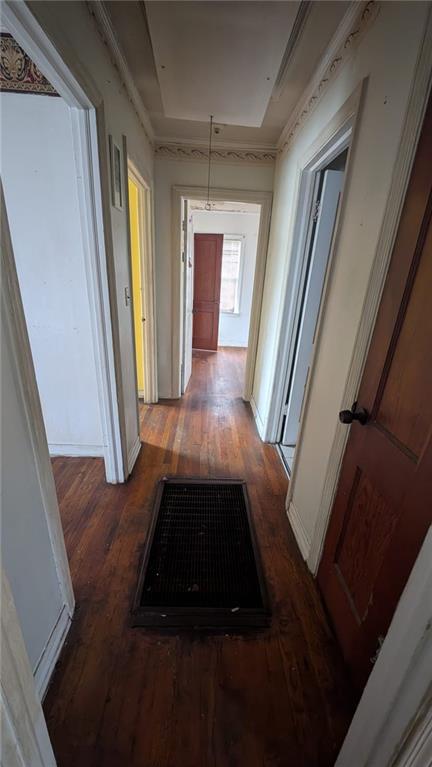 corridor featuring a tray ceiling and dark wood-type flooring