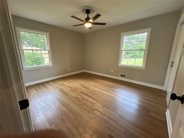 empty room featuring hardwood / wood-style floors, ceiling fan, and a wealth of natural light