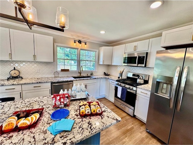 kitchen with white cabinets, stainless steel appliances, light wood-type flooring, decorative light fixtures, and sink