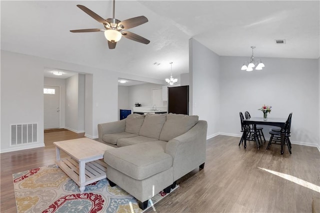 living area featuring wood finished floors, baseboards, vaulted ceiling, and visible vents