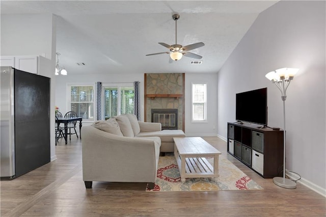 living room with plenty of natural light, vaulted ceiling, and a fireplace