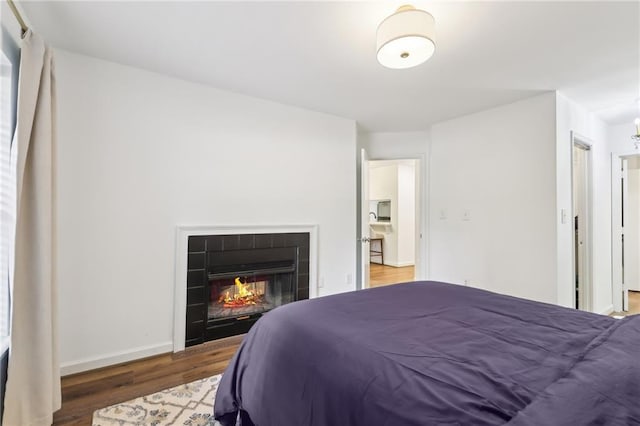 bedroom with a closet, hardwood / wood-style floors, and a tile fireplace