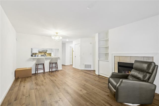 interior space with a notable chandelier, a fireplace, and light wood-type flooring