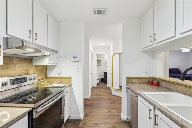 kitchen with dark wood-type flooring, sink, white cabinets, stainless steel appliances, and backsplash