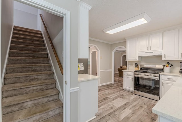 kitchen with white cabinets, light wood-type flooring, and stainless steel range with gas cooktop