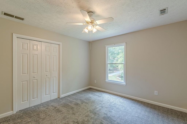 unfurnished bedroom with a closet, ceiling fan, carpet floors, and a textured ceiling