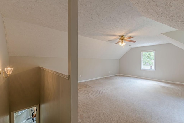 additional living space with carpet floors, a textured ceiling, vaulted ceiling, and ceiling fan