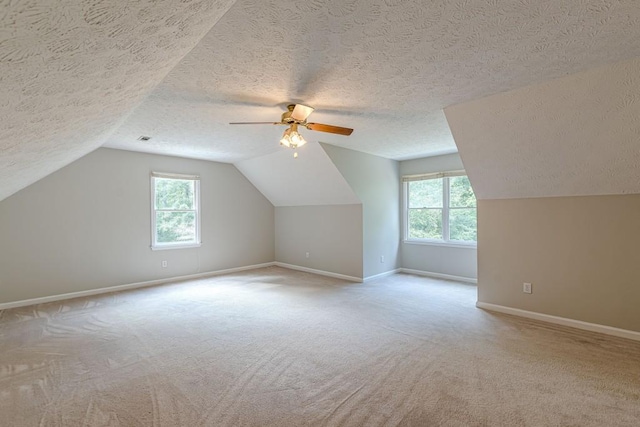 additional living space featuring a textured ceiling, lofted ceiling, light carpet, and ceiling fan