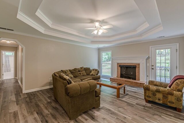 living room featuring ceiling fan, hardwood / wood-style flooring, a fireplace, and a healthy amount of sunlight