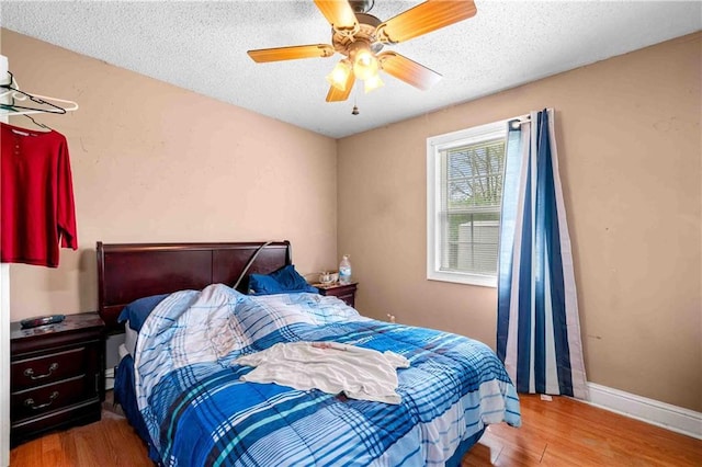bedroom with baseboards, a textured ceiling, wood finished floors, and ceiling fan