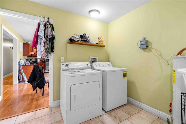 laundry area with water heater, light tile patterned floors, washing machine and dryer, and laundry area