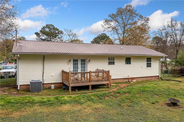 back of property with french doors, cooling unit, a deck, metal roof, and a lawn