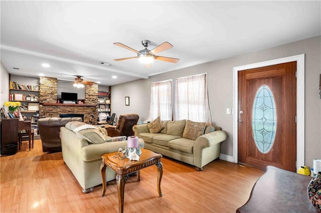 living area featuring visible vents, light wood-style floors, a wealth of natural light, and ceiling fan