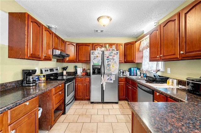 kitchen with appliances with stainless steel finishes, a textured ceiling, dark countertops, under cabinet range hood, and visible vents